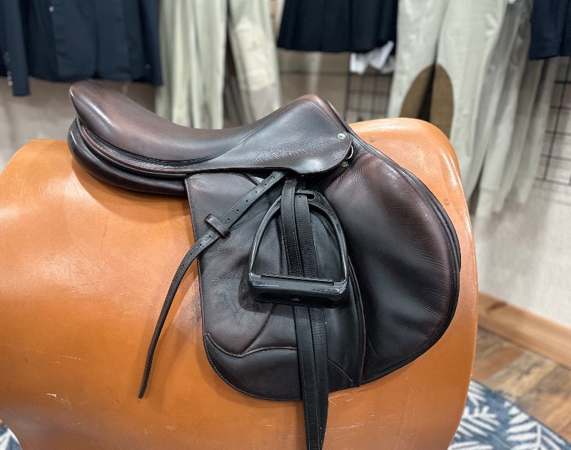 Dark leather english saddle  with padded knee rolls. Stirrup leathers and black stirrups