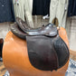 Side view of a brown leather english saddle with a wide flap and high cantle.