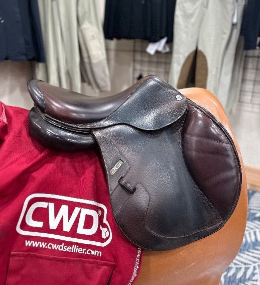 right side view of the English cwd equestrian saddle with two toned leather sitting on red saddle cover both sitting on brown saddle model with equestrian show pants and black show coats in the background