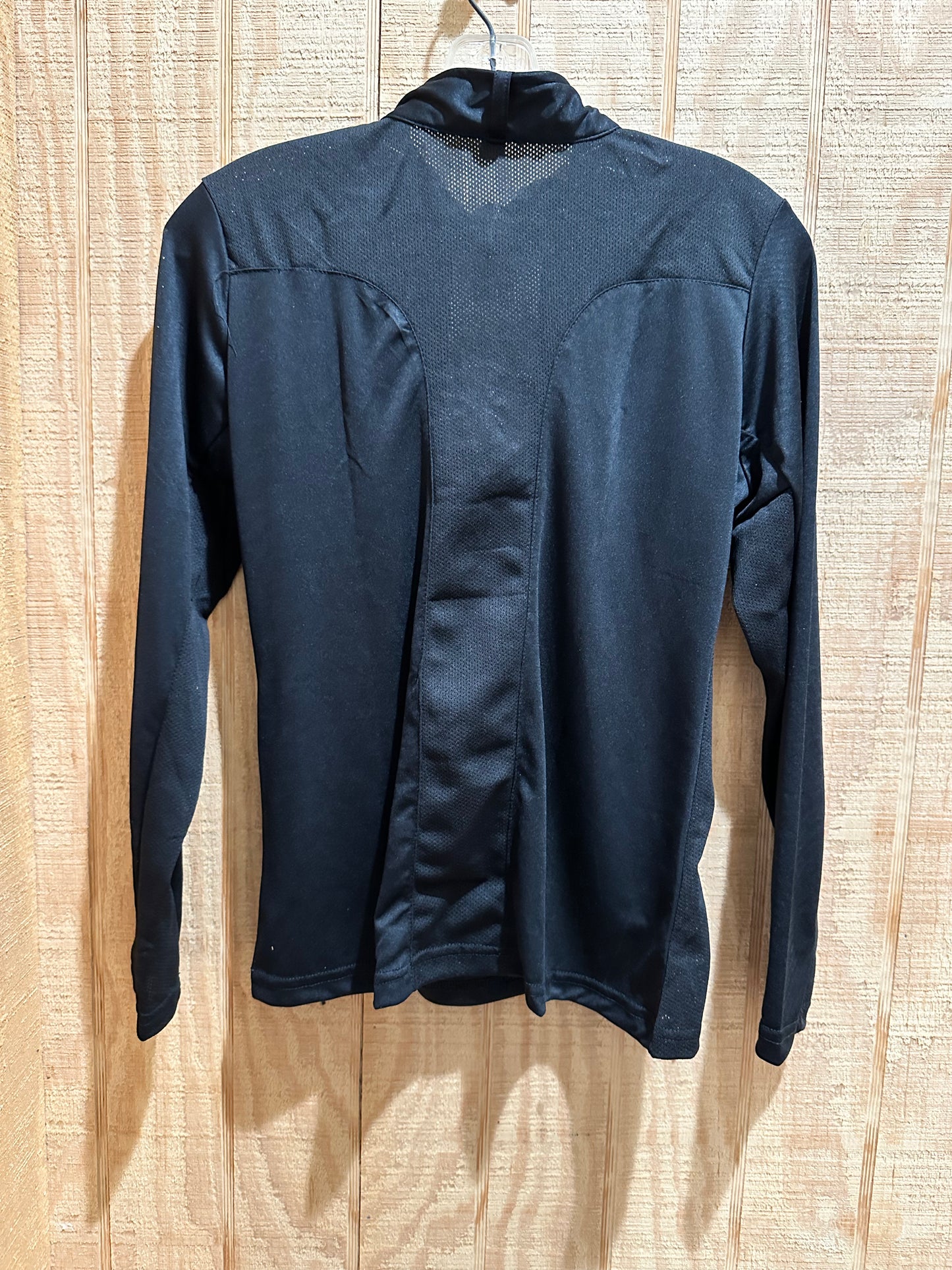 black long sleeve riding shirt with the back of the shirt facing out against light colored wood 