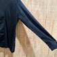 right sleeve of a black long sleeve riding shirt hung up against light colored wood
