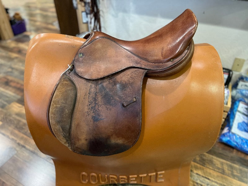 Brown old leather saddle with suede knee rolls. 