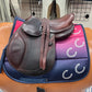 Youth english saddle with padded knee rolls sitting on a colorful pad with decorative horseshoes printed.