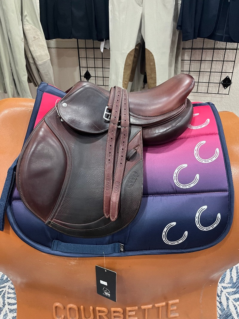 Youth english saddle with padded knee rolls sitting on a colorful pad with decorative horseshoes printed.