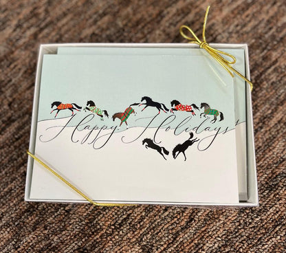 Boxed holiday cards picturing frolicking horses in christmas colored blanks over the words Happy Holidays