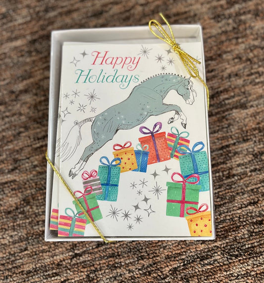 Box holiday cards picturing a dapple grey horse jumping over presents