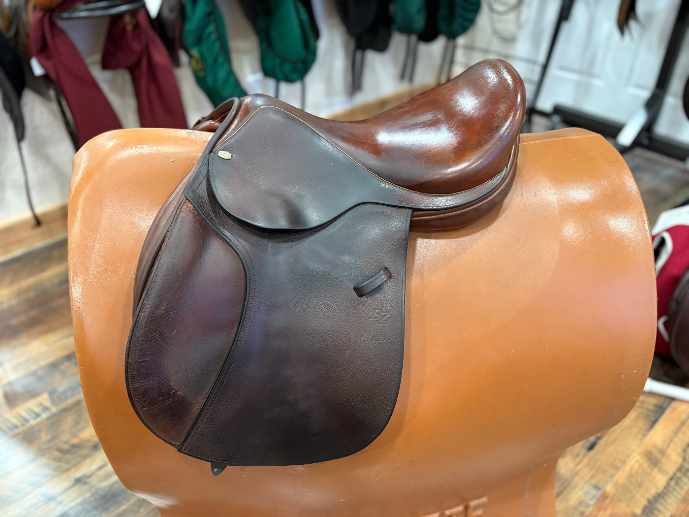 Brown leather english style saddle with knee rolls on a tan solid stand