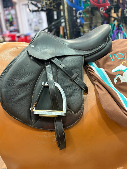 Dark leather english saddle shown with safety stirrups and Voltaire logo'd cover