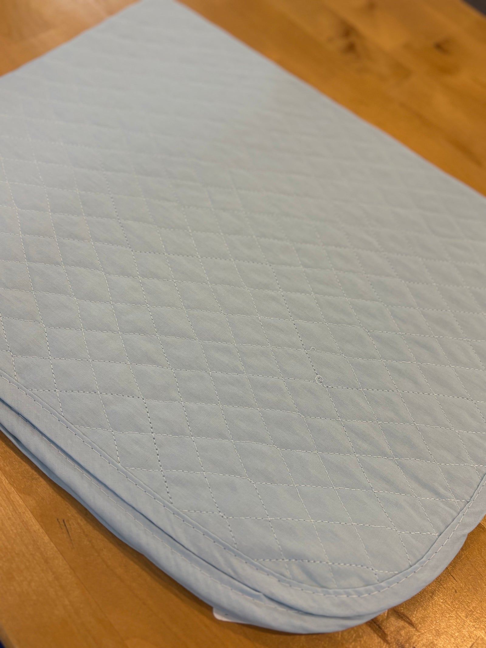 Light blue quilted saddle pad on a wooden surface