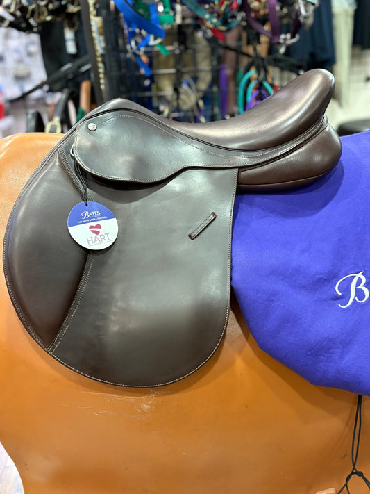 Dark brown leather english saddle shown with a purple saddle cover behind it.
