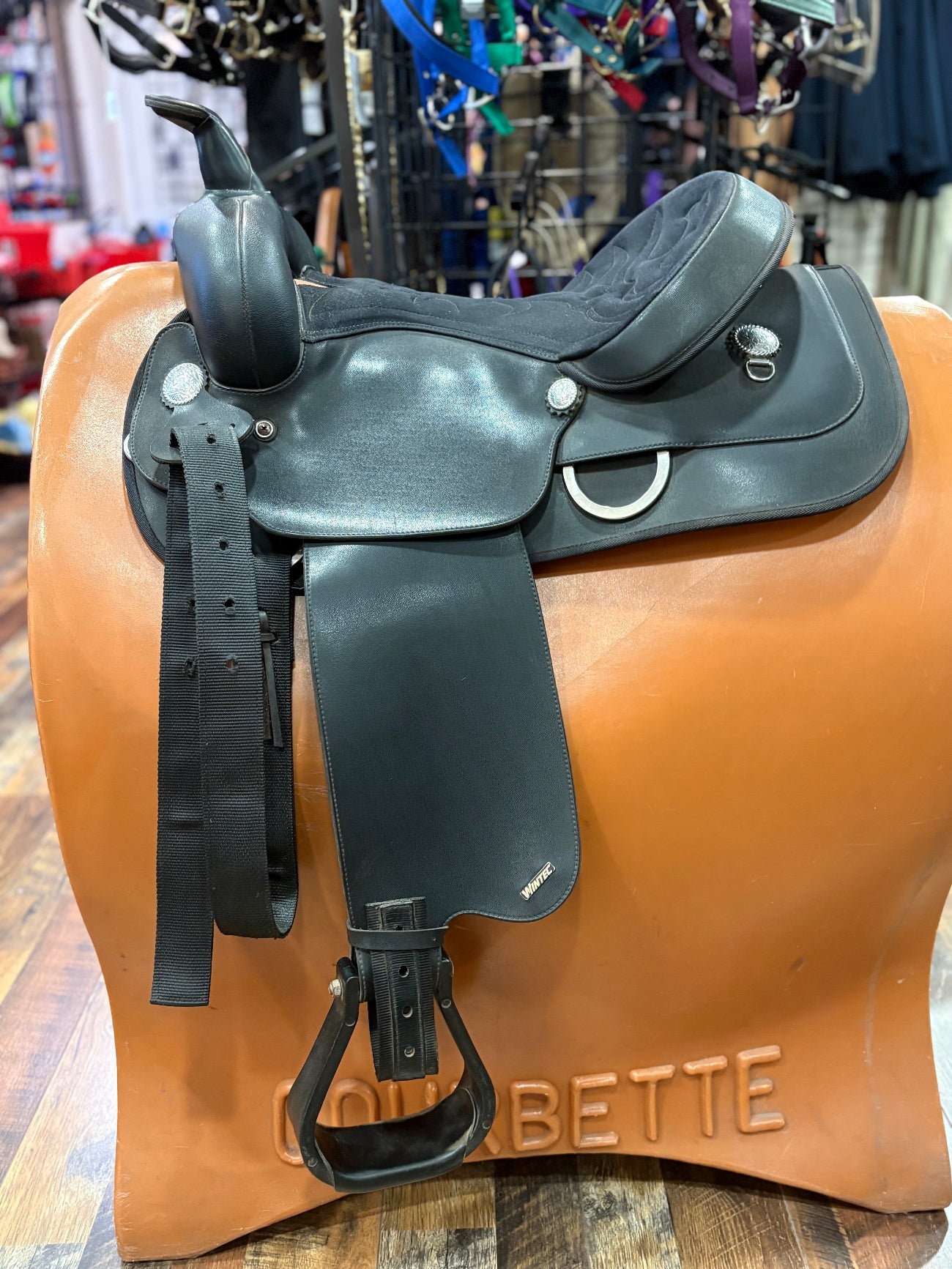 Black western saddle on a tan saddle stand