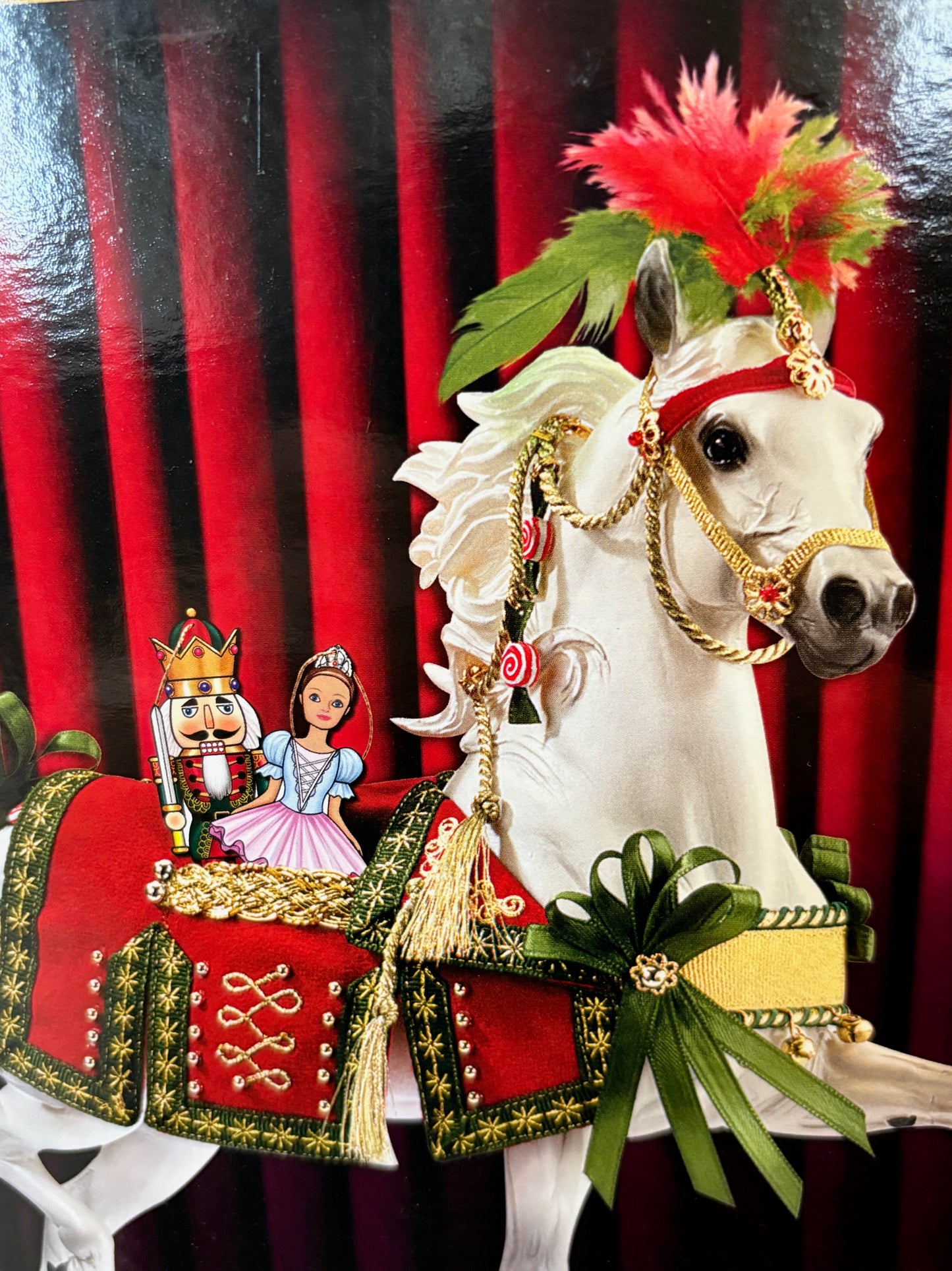 Decorative white horse figurine with gold bridle and red and green decorations on a red and black striped background.