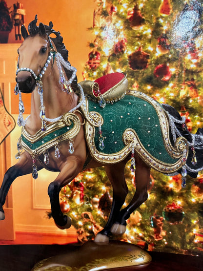 Decorative buckskin horse figure with green and gold details in front of a Christmas tree.