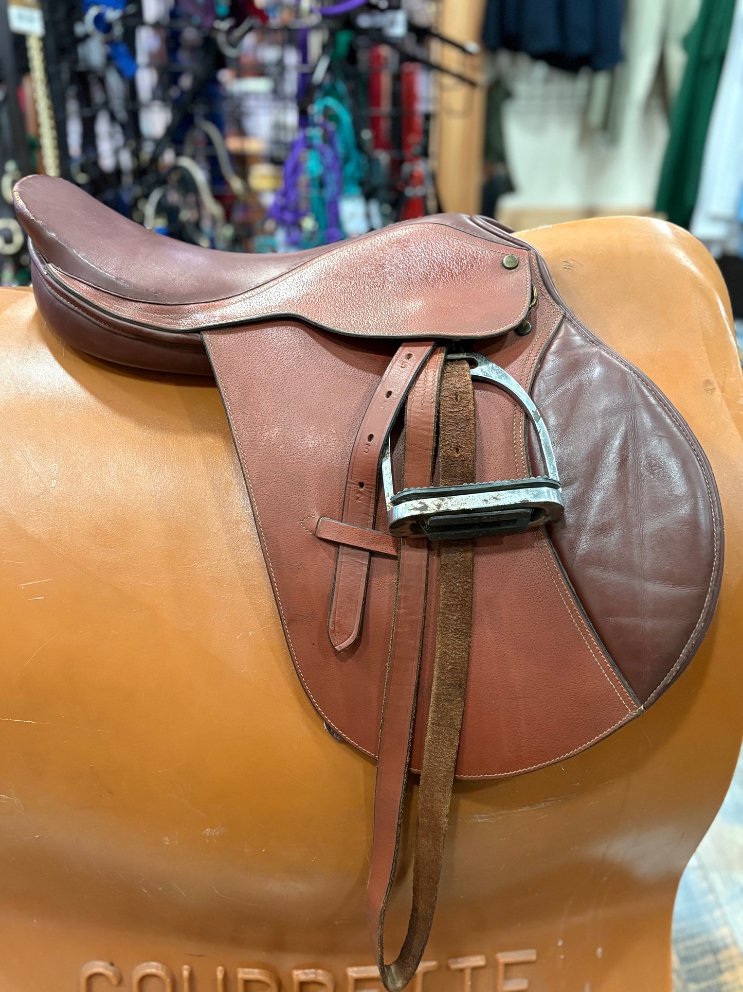 Brown leather saddle on a stand with a blurred background
