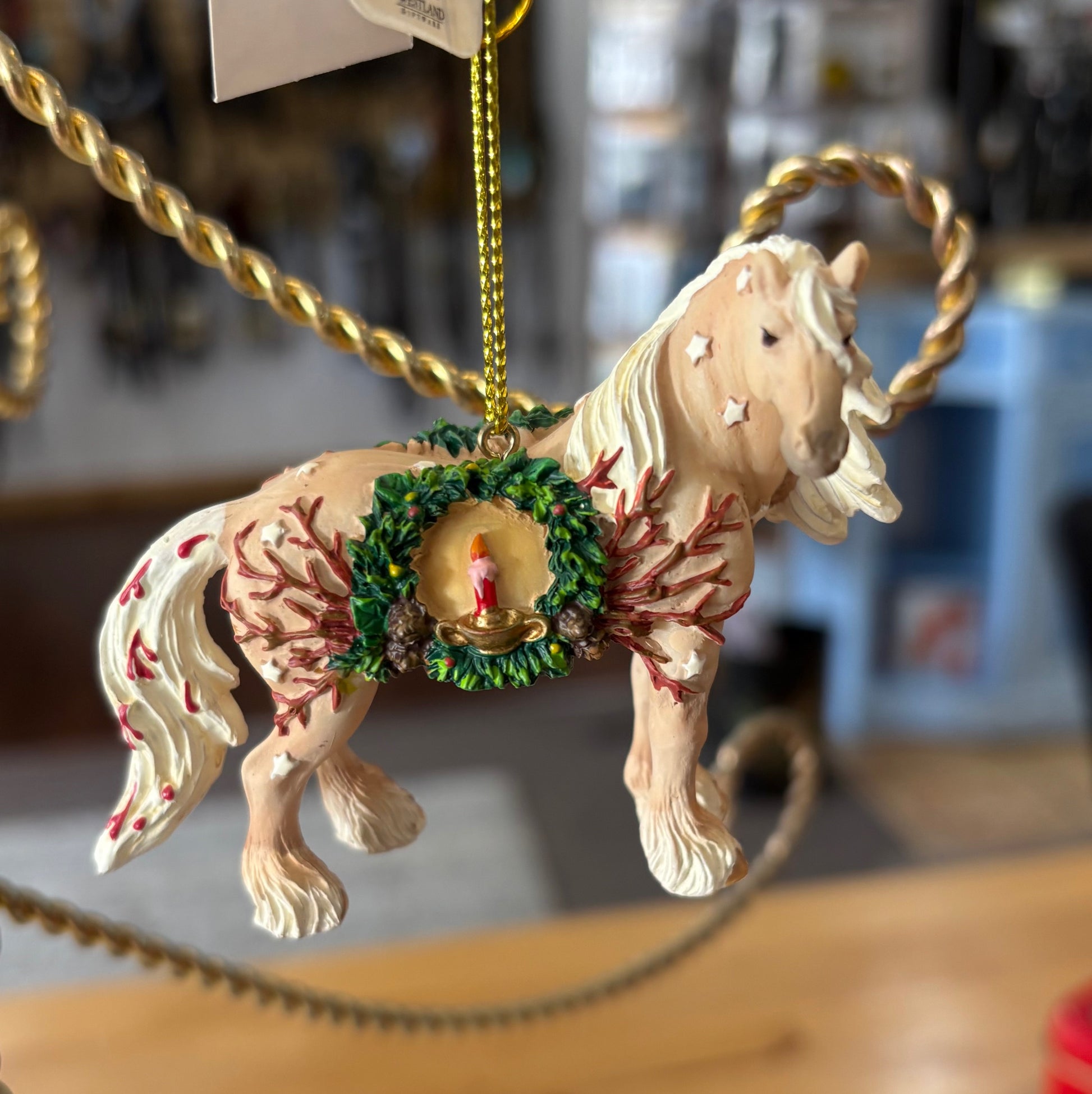 Decorative horse ornament with flowing flaxen mane and feathers hanging on a gold chain.