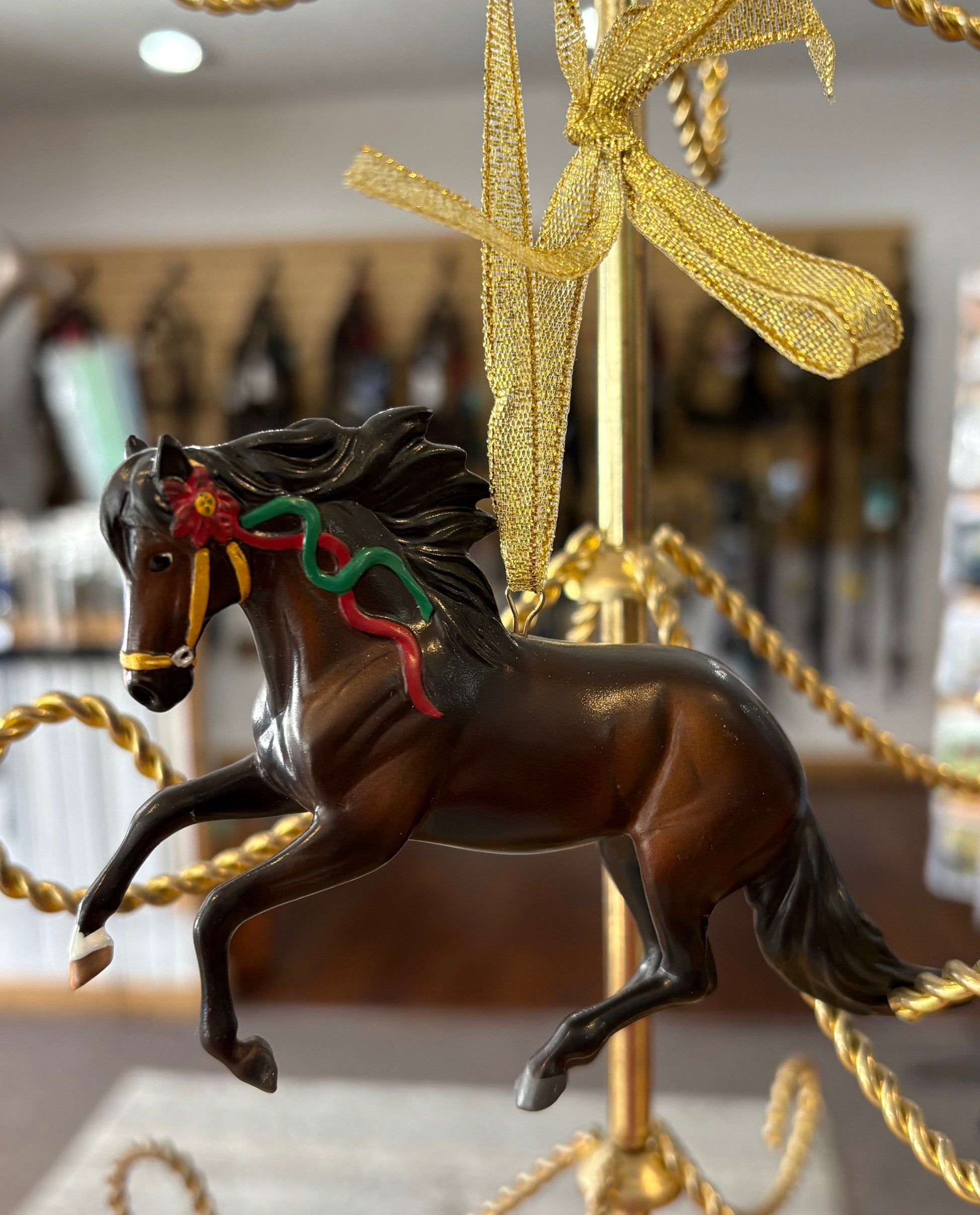 Decorative dark bay horse ornament with a gold bow on a blurred background