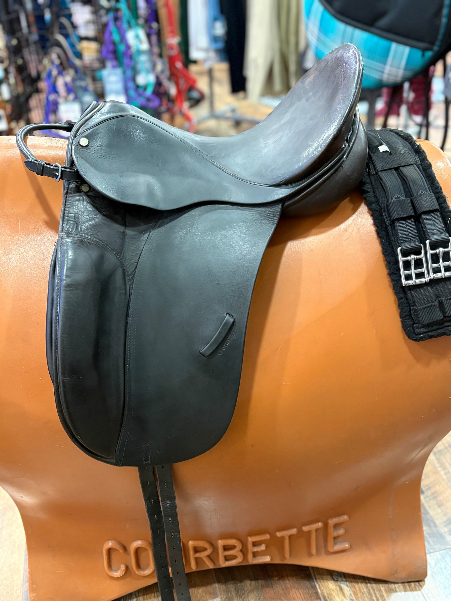 Black leather dressage saddle shown with a black fleece girth.