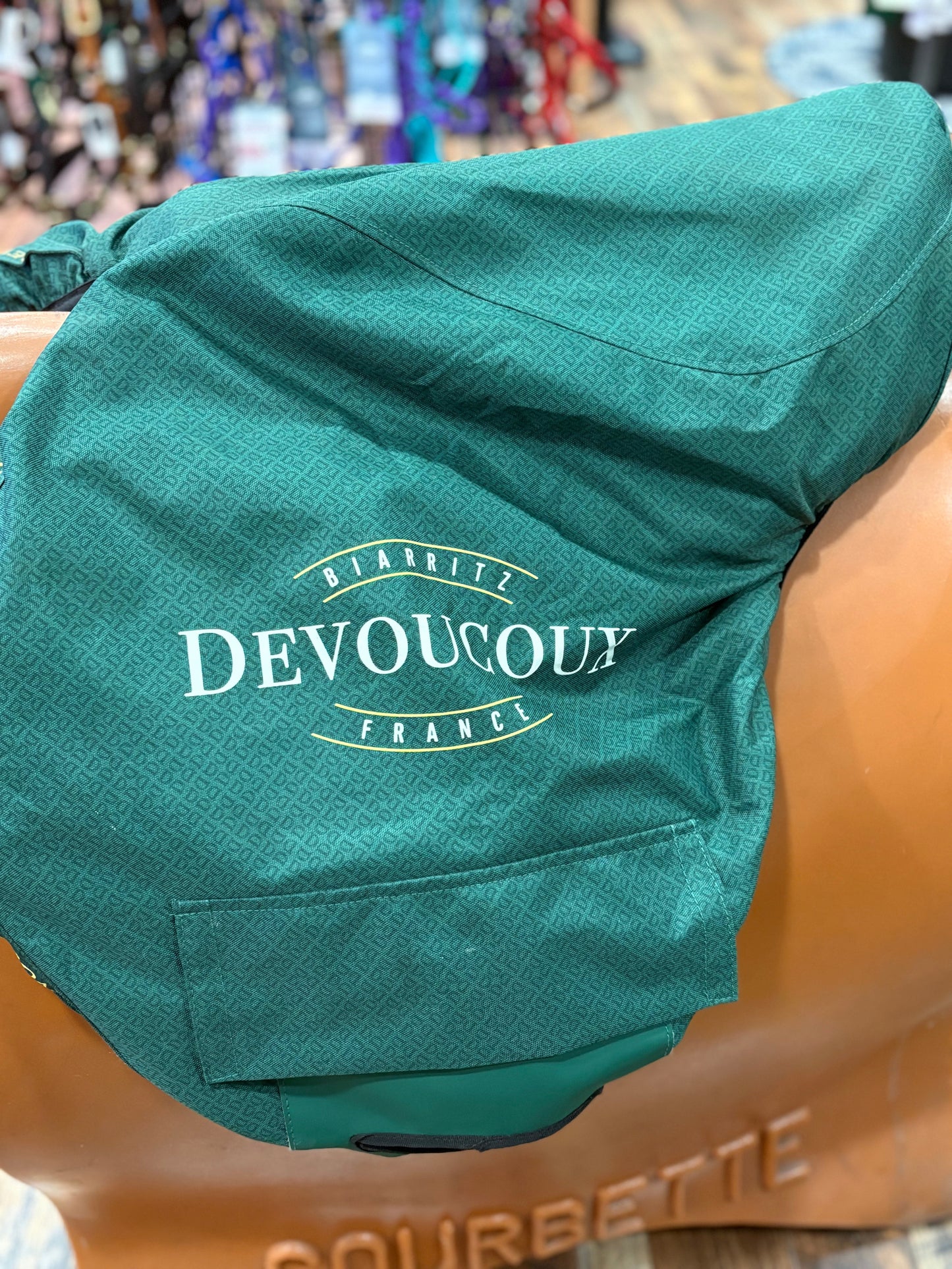 English saddle covered in a green saddle cover with DEVOUCOUX logo