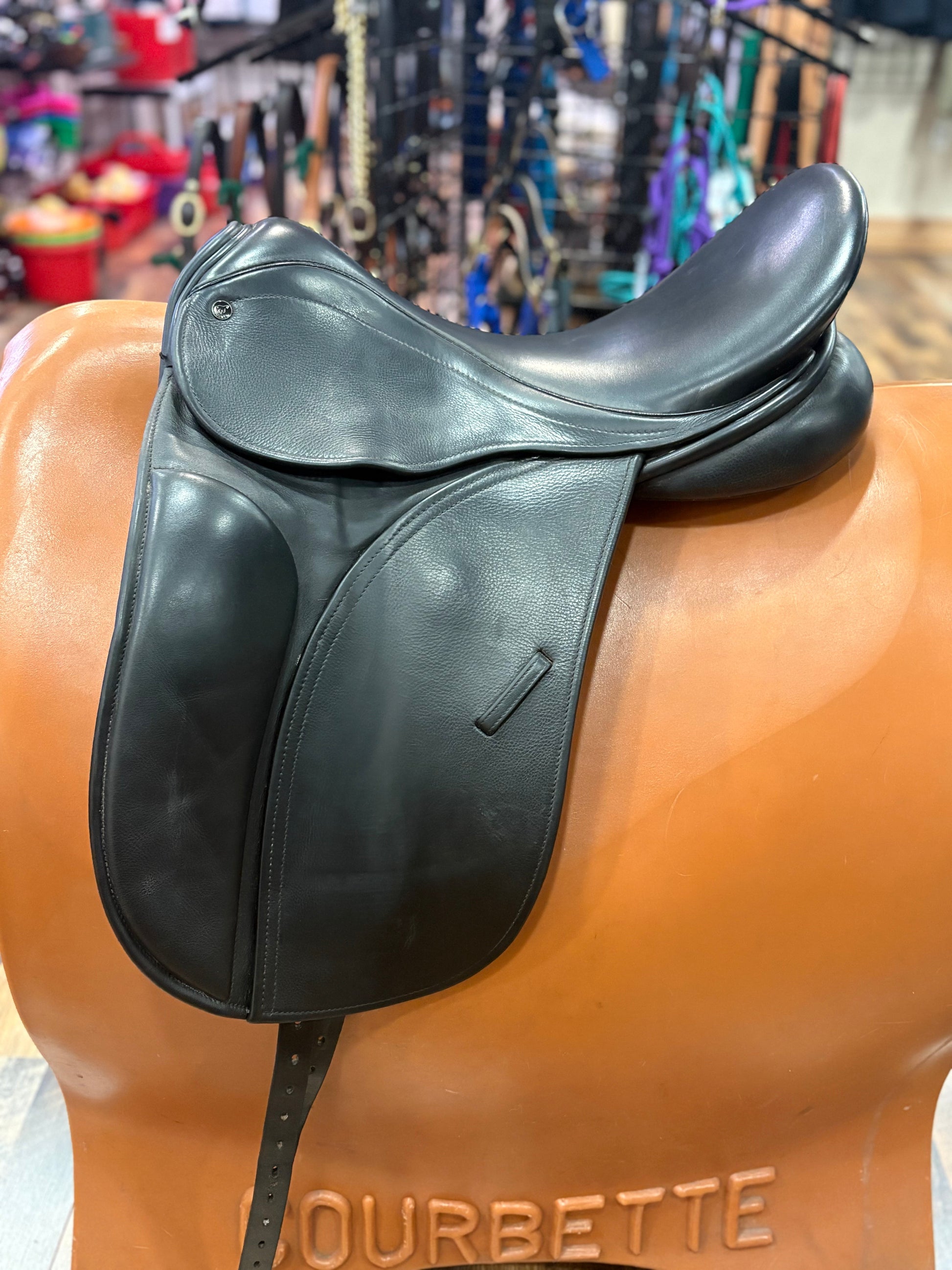 Black leather dressage saddle on a stand.