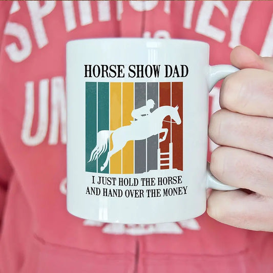 "Horse Show Dad" coffee mug showing a horse jumping a jump with the saying "I just hold the horse and hand over the money