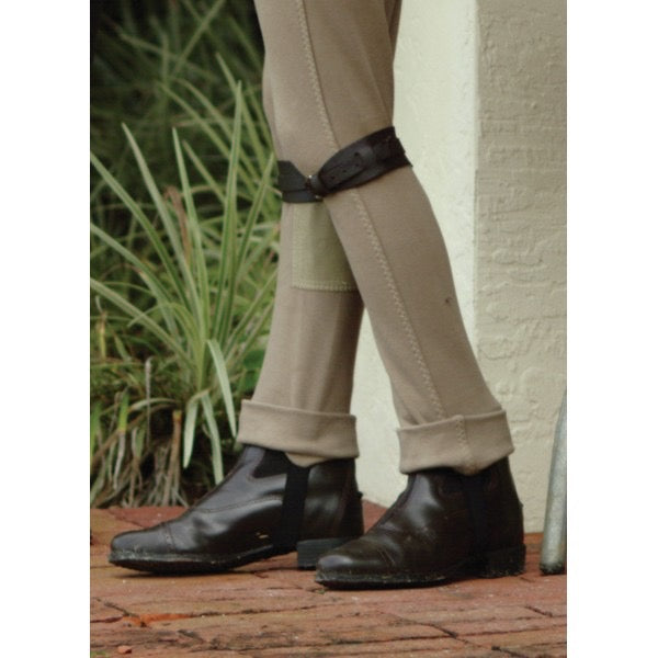 a pair of young equestrian legs wearing paddock boots, tan jobs, and leather garter straps just below the knee