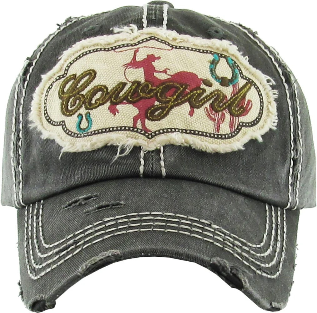 distressed grey ball cap with white stitching.  front has a silhouette of a rodeo rider and "Cowgirl"