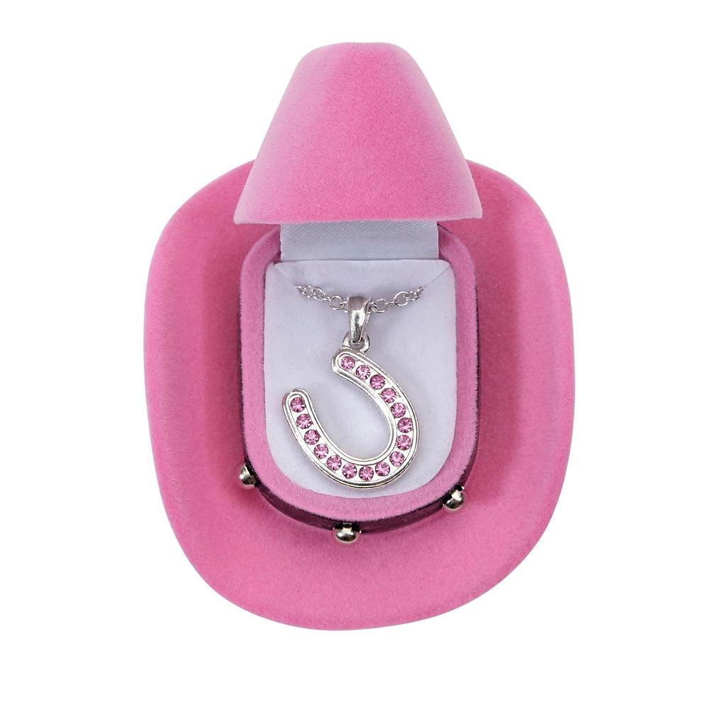 Horseshoe pendant with pink colored stones shown in a pink cowboy shaped box