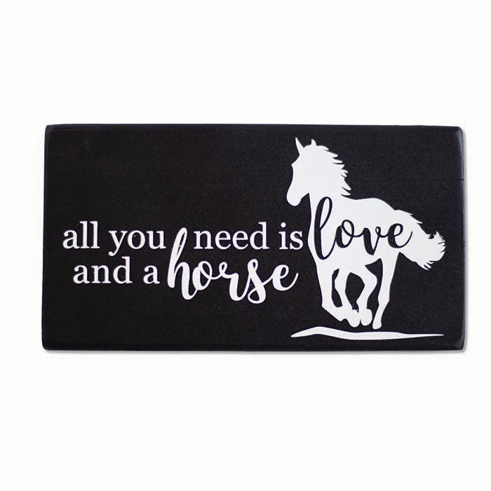 Black wooden block with "all you need is love and a horse" written in white with a white silhouette of a galloping horse