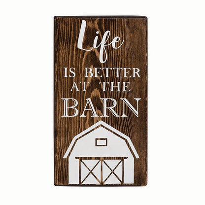 wooden block with "Life is better at the barn" written in white with a white silhouette of a barn