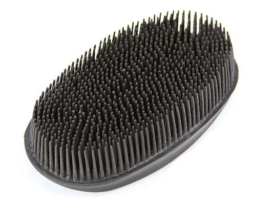 Black rubber bristle face brush on a white background