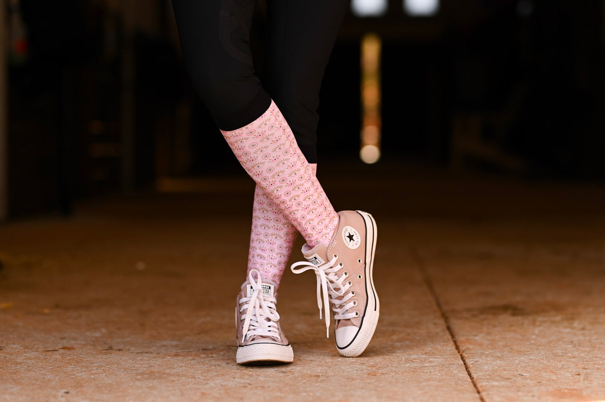 Person wearing pink socks and beige sneakers on a dark background