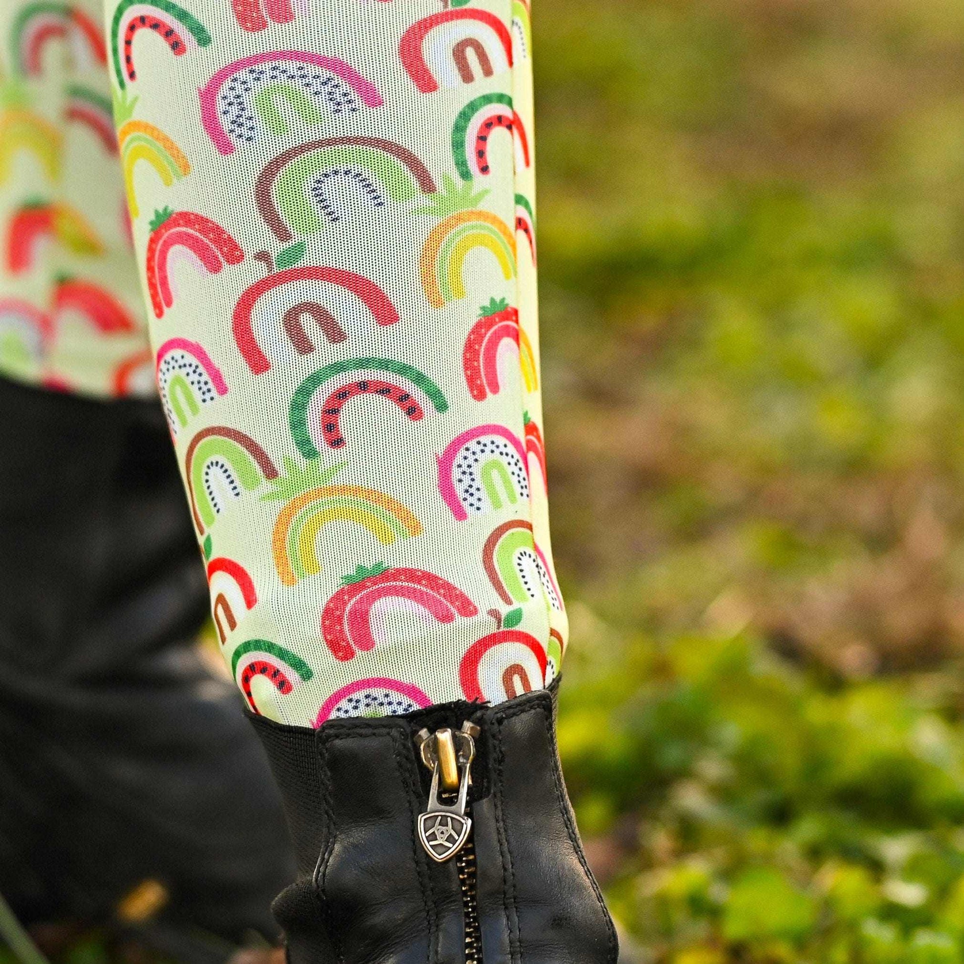 Colorful rainbow-patterned knee socks on a person's legs with a blurred green background.