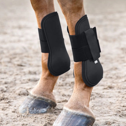 Horse legs wearing black protective leg wraps on a gravel surface