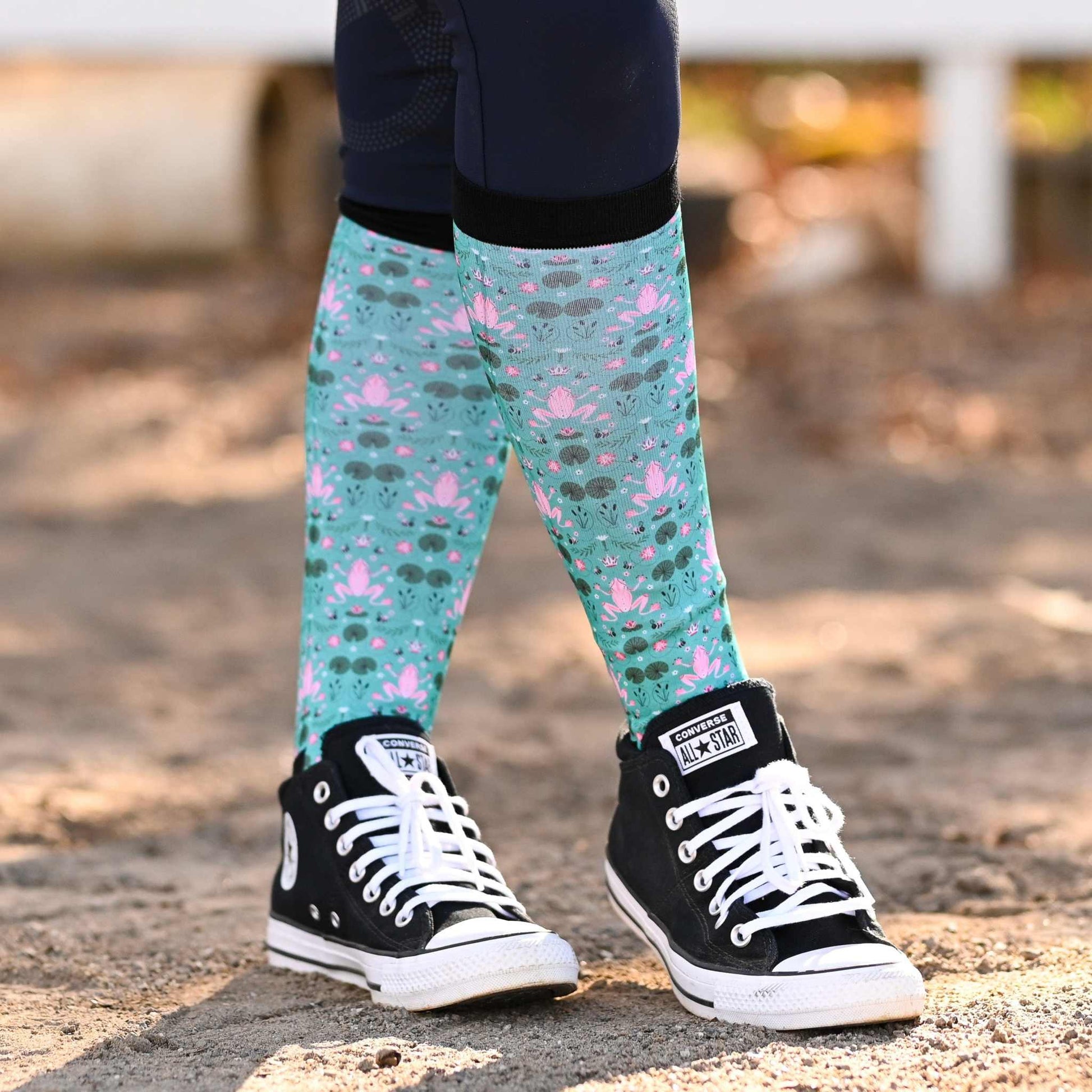 Colorful patterned knee socks with frog themed design on a blurred background
