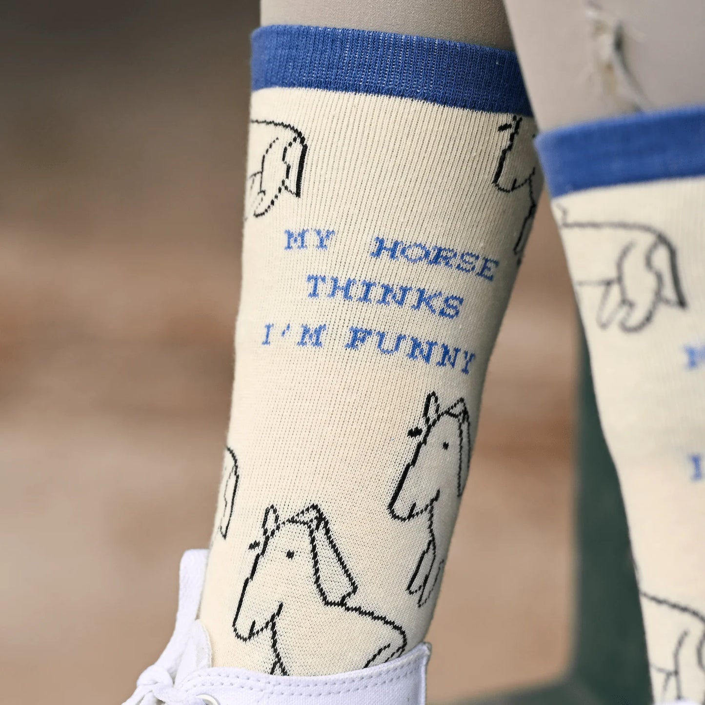 Socks with horse illustrations and text 'My horse thinks I'm funny' on a blurred background