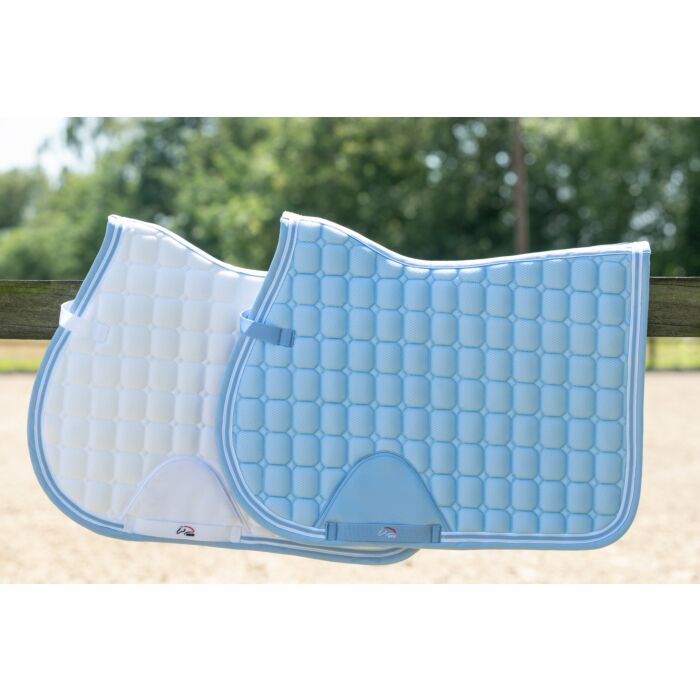 two equestrian saddle pads one white with blue piping laying 3/4ths underneath blue saddle pad with white piping, both sitting on a wooded fence beam with blurred trees in the background  