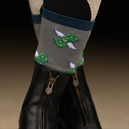 Gray sock with green dollar bill design worn by a person wearing black paddock boots