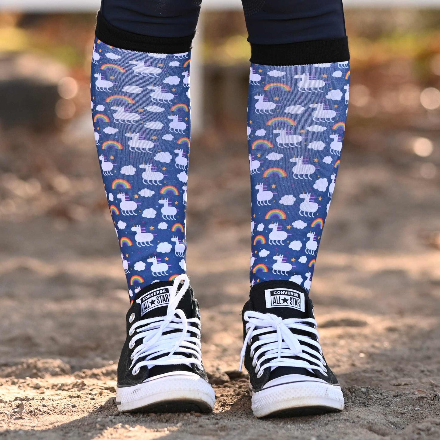 Blue patterned knee socks worn by a person with black and white sneakers on a blurred outdoor background