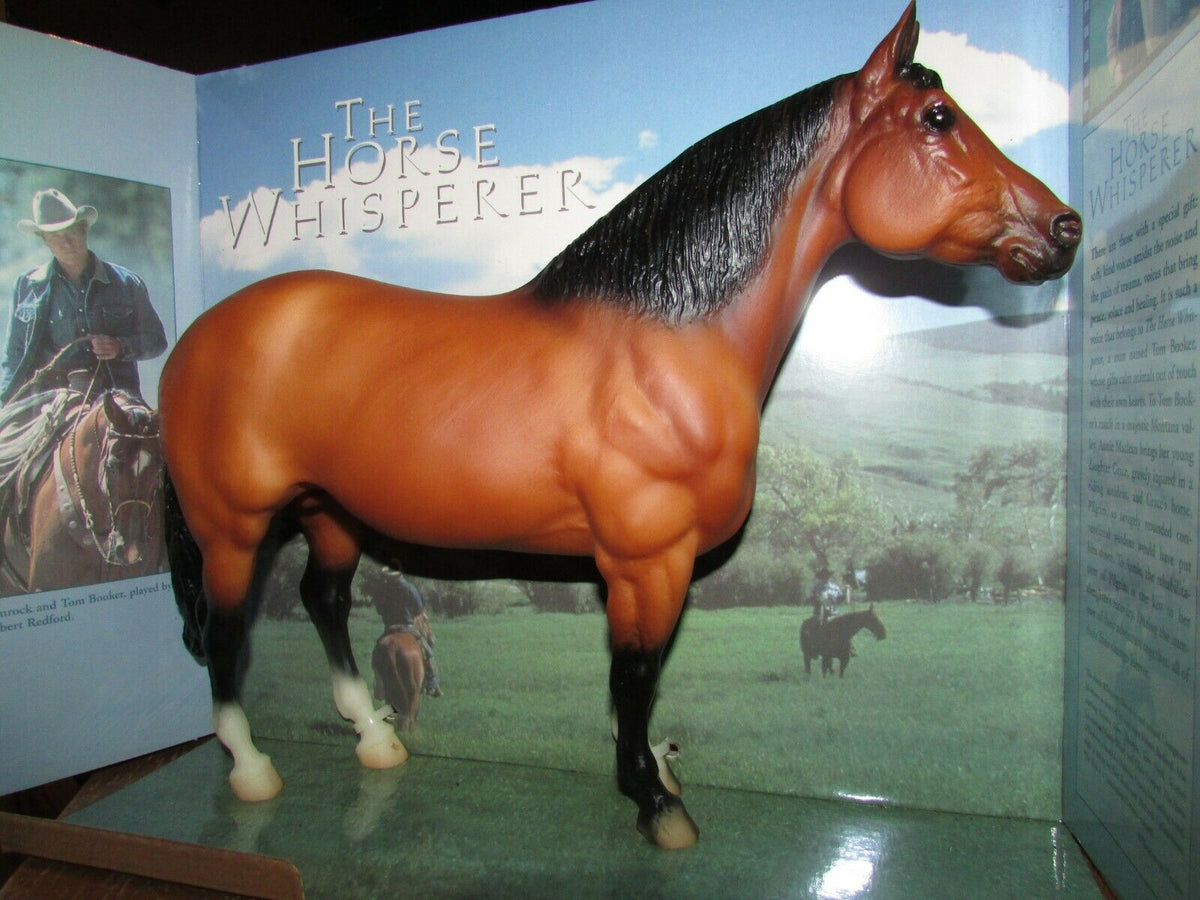 A detailed plastic model of a horse named 'The Horse Whisperer' displayed  in front of a themed backdrop showing a cowboy and landscape scenery.