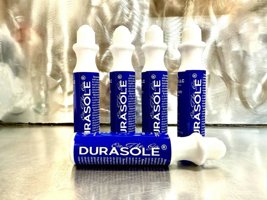 Multiple Durasole On the Go products on a reflective surface with a metallic background