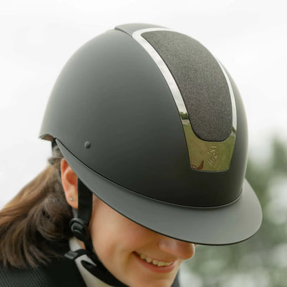 Person wearing a black riding helmet with a touch of chrome and subtle sparkle.