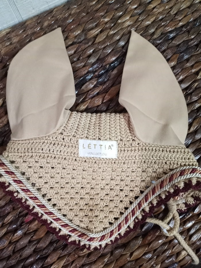 Tan colored crochet fly bonnet for a horse. Burgundy cord trim.  Lettia logo.