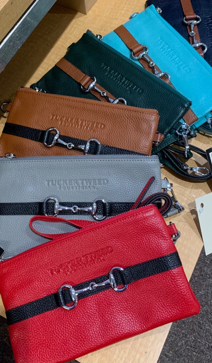 Fanned out display of colorful leather wristlets featuring a contrasting leather stripe with a snaffle bit decoration.