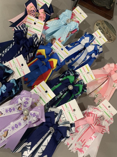 Multiple sets of various colored equestrian show bows.