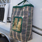 Large horse's hay bag in green and tan plaid shown hanging off of an equine trailer