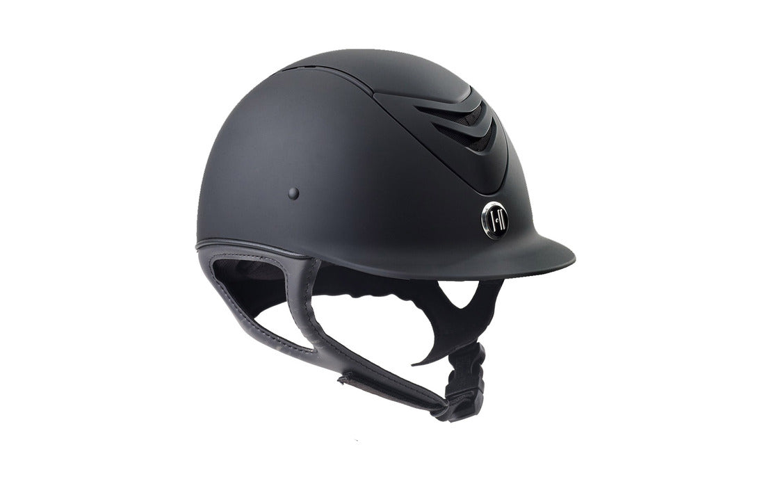 Black matte equestrian hard shell  riding helmet with leather look buckle  chin strap.  Logo in front center below vents.
